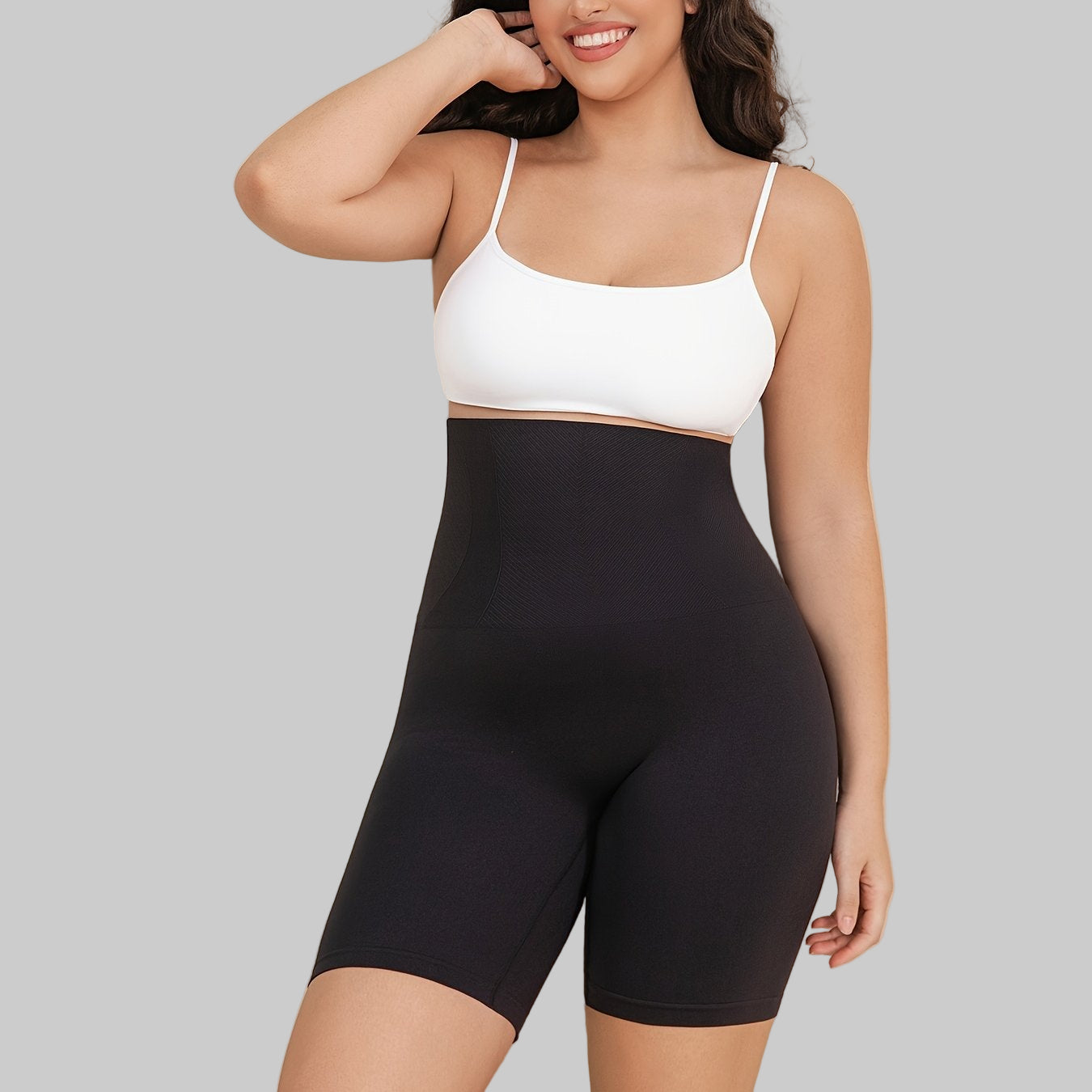 Woman wearing a white sports bra and black shorts against a beige background